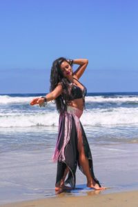 Girl belly dancing on the beach.